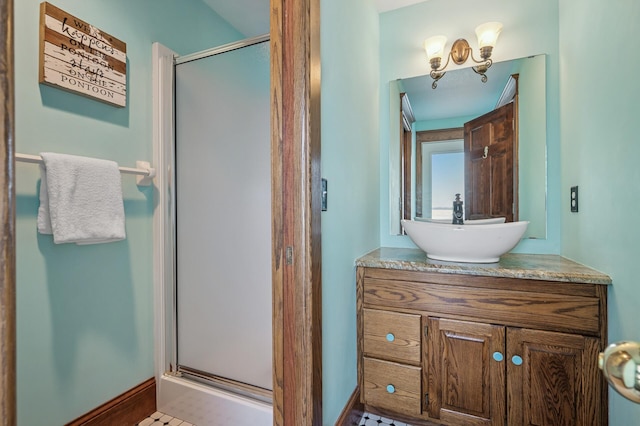 full bath featuring a stall shower, vanity, and baseboards