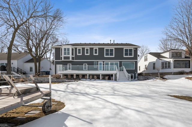 snow covered rear of property featuring stairs