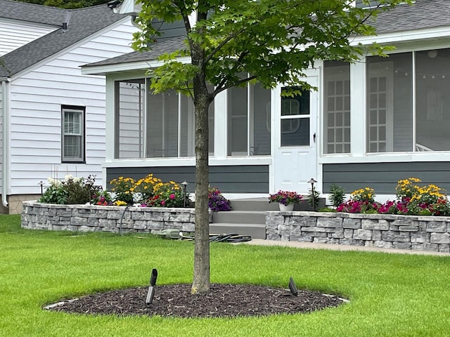 view of side of property with a yard, a sunroom, and a shingled roof