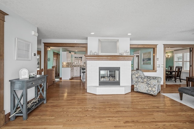 255 Shore Dr, Forest Lake, MN 55025 - living room featuring a textured ceiling, a brick fireplace, light wood-type flooring, and recessed lighting