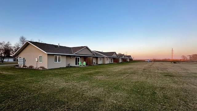 property exterior at dusk featuring a lawn