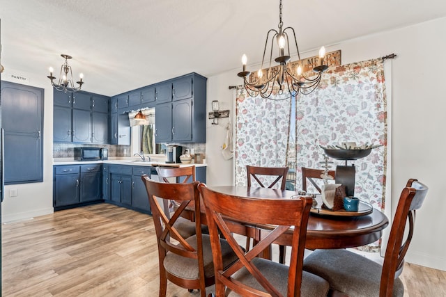 dining space featuring sink, light hardwood / wood-style flooring, and a chandelier