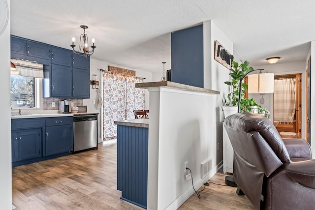 kitchen with hanging light fixtures, hardwood / wood-style flooring, stainless steel dishwasher, and blue cabinets