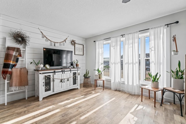 living room with wood-type flooring, a textured ceiling, and wood walls