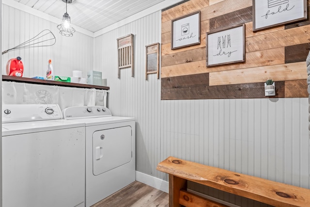 clothes washing area featuring independent washer and dryer, wooden walls, and light wood-type flooring