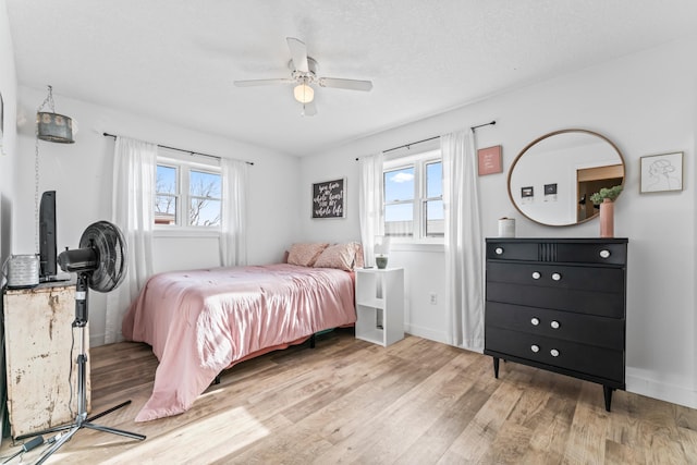 bedroom with ceiling fan, light hardwood / wood-style floors, and multiple windows