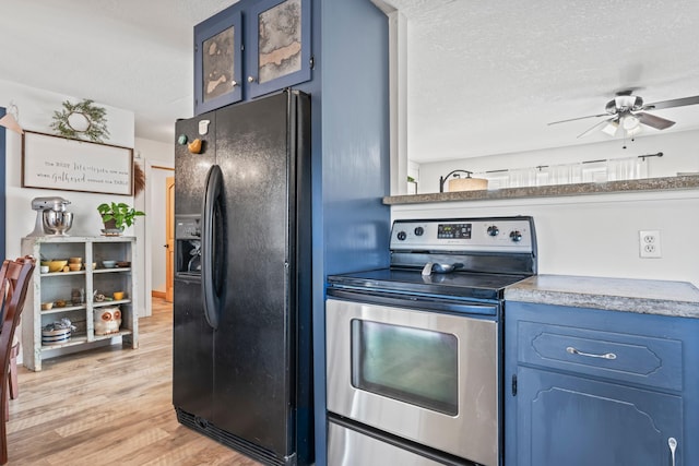 kitchen featuring electric stove, blue cabinetry, black refrigerator with ice dispenser, and a textured ceiling