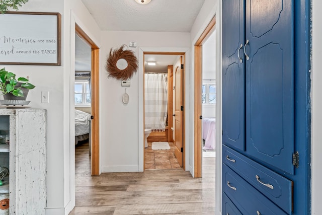 corridor featuring light hardwood / wood-style floors and a textured ceiling