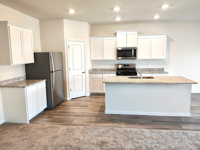 kitchen with white cabinetry, stainless steel appliances, and an island with sink