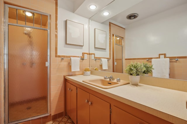 bathroom with vanity, tile walls, and a shower with shower door