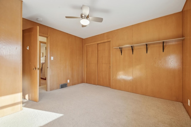 carpeted empty room with wooden walls and ceiling fan