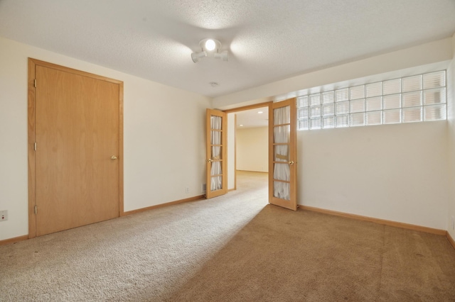 carpeted spare room featuring french doors and a textured ceiling