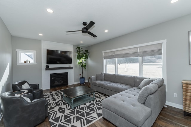 living room featuring a fireplace, dark wood-type flooring, and ceiling fan