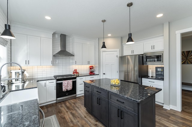 kitchen featuring pendant lighting, appliances with stainless steel finishes, wall chimney exhaust hood, and white cabinets