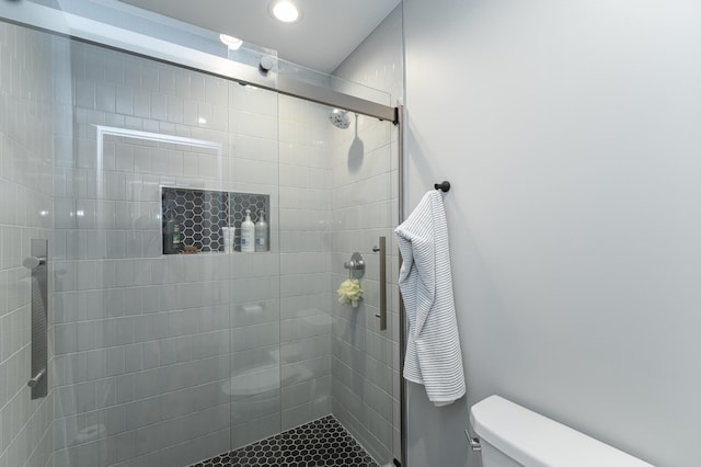 bathroom featuring a shower with door and toilet