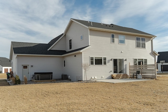 rear view of property with a hot tub, cooling unit, a lawn, and a patio area