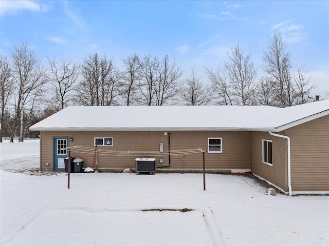 snow covered rear of property with central AC unit