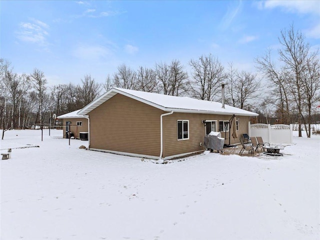 snow covered rear of property with an outdoor fire pit