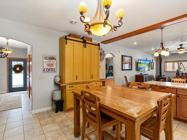 dining space with a notable chandelier, light tile patterned floors, a barn door, and a textured ceiling