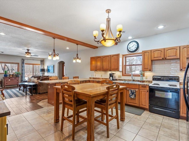 kitchen with plenty of natural light, electric stove, sink, decorative backsplash, and pendant lighting