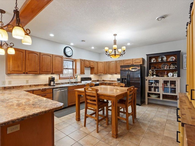 kitchen featuring a chandelier, sink, pendant lighting, stainless steel appliances, and tasteful backsplash