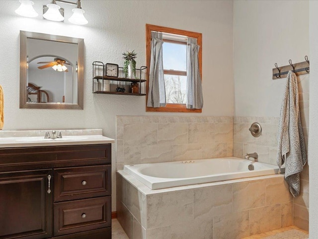 bathroom featuring ceiling fan, vanity, and a relaxing tiled tub