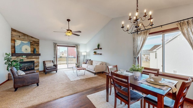 dining area featuring ceiling fan with notable chandelier, high vaulted ceiling, a fireplace, and hardwood / wood-style floors