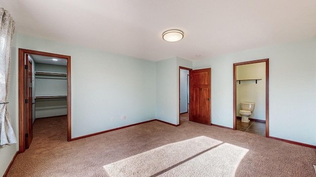 unfurnished bedroom featuring connected bathroom, a walk in closet, a closet, and carpet