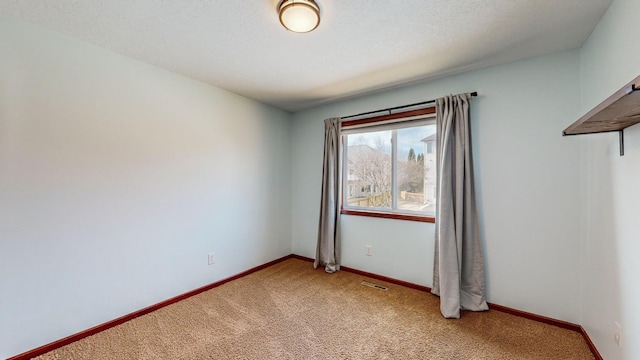 carpeted empty room with a textured ceiling