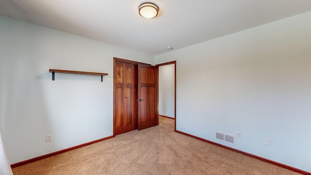 unfurnished bedroom with light colored carpet and a closet