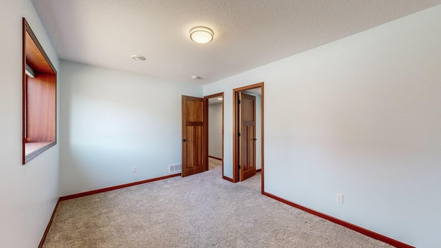 spare room with light colored carpet and a textured ceiling