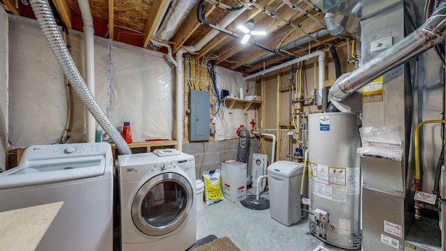 clothes washing area with gas water heater, electric panel, and washing machine and dryer