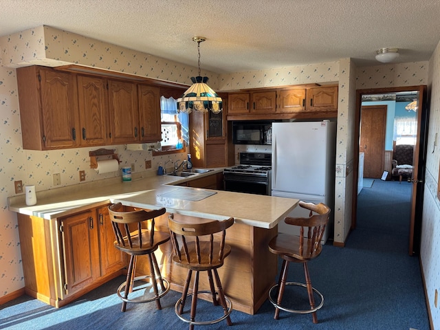 kitchen featuring pendant lighting, sink, range, white refrigerator, and a textured ceiling