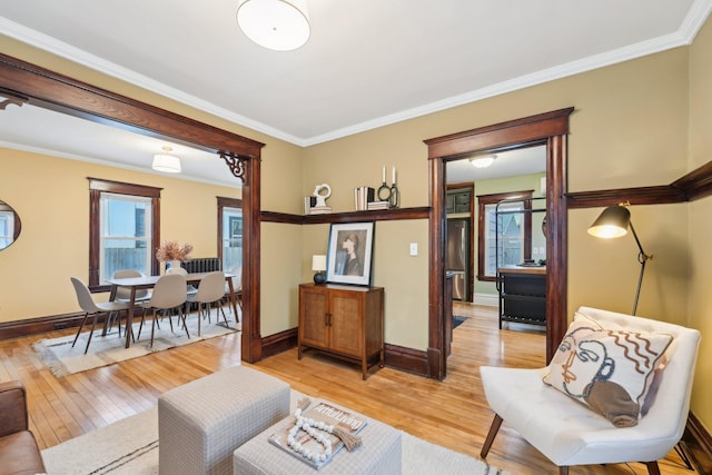 living room with plenty of natural light, ornamental molding, and light wood-type flooring