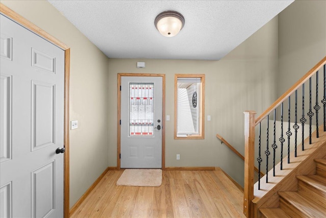 foyer entrance with a textured ceiling and light wood-type flooring