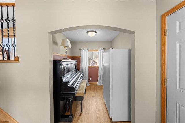 kitchen featuring light wood-type flooring, a textured ceiling, and white fridge