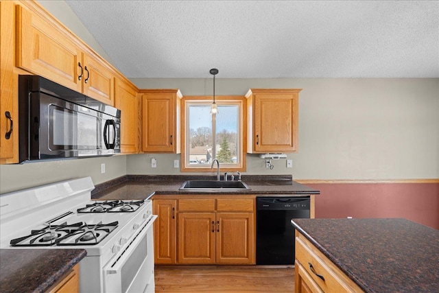 kitchen featuring sink, light hardwood / wood-style flooring, hanging light fixtures, black appliances, and a textured ceiling