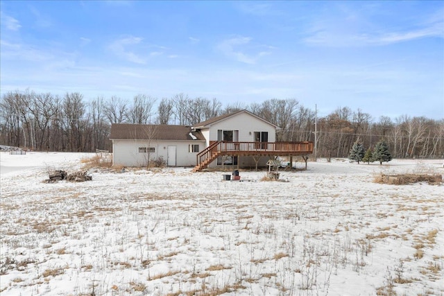 snow covered back of property with a wooden deck