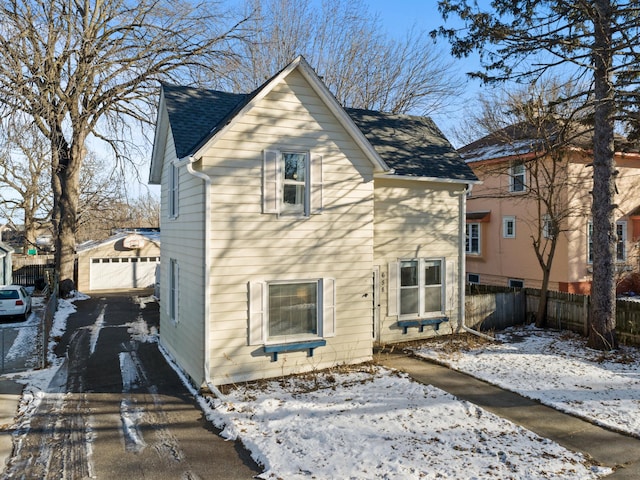 snow covered property featuring a garage and an outdoor structure