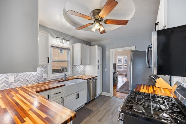 kitchen with sink, white cabinetry, wooden counters, stainless steel appliances, and backsplash