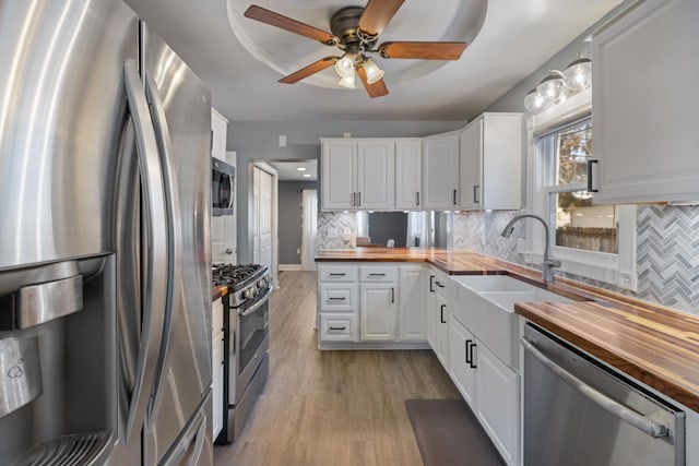 kitchen featuring wood counters, backsplash, stainless steel appliances, and white cabinets