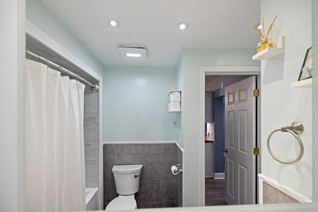 bathroom featuring tile walls, shower / tub combo with curtain, and toilet