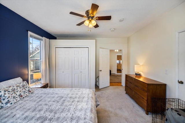 bedroom with ceiling fan, light carpet, and a closet