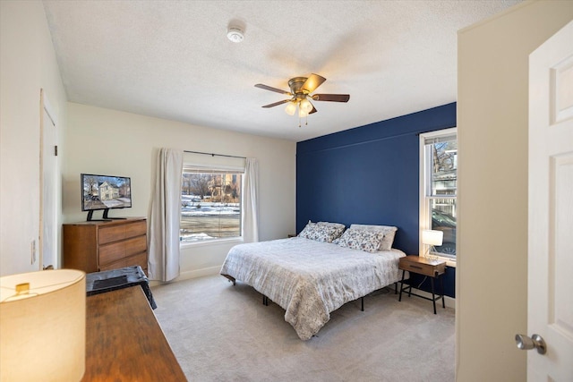 carpeted bedroom with ceiling fan, multiple windows, and a textured ceiling