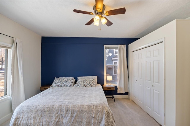 carpeted bedroom featuring ceiling fan and a closet