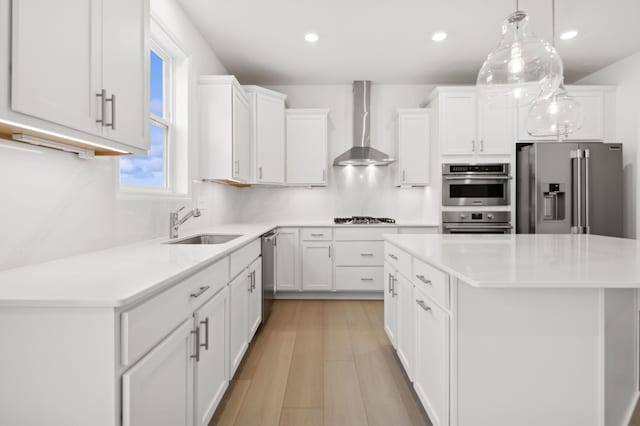 kitchen with stainless steel appliances, white cabinetry, a center island, and wall chimney exhaust hood