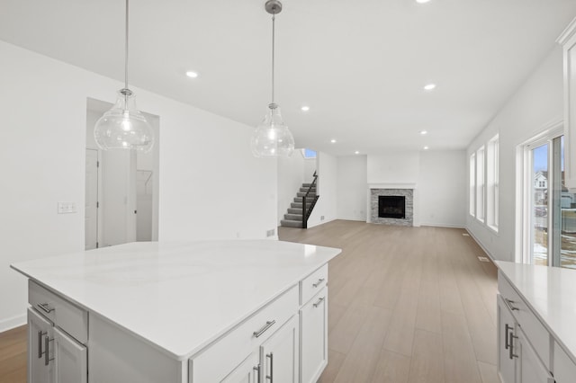 kitchen with white cabinetry, decorative light fixtures, light hardwood / wood-style floors, and a kitchen island