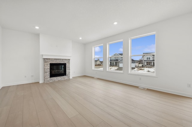 unfurnished living room featuring a fireplace and light hardwood / wood-style floors