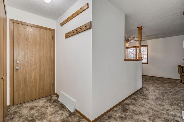 carpeted foyer entrance with a textured ceiling, baseboards, a ceiling fan, and visible vents