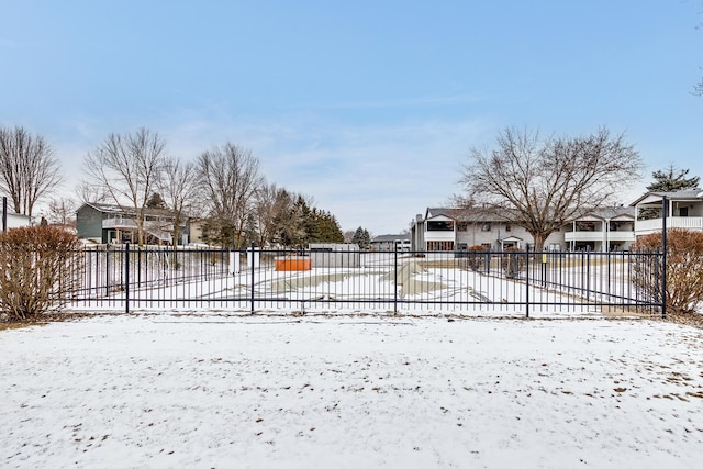 snow covered gate with a residential view and fence
